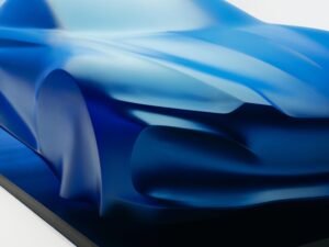 Scultura della futura Alpine A110 coperta da un velo blu, ispirata a leggerezza e aerodinamica